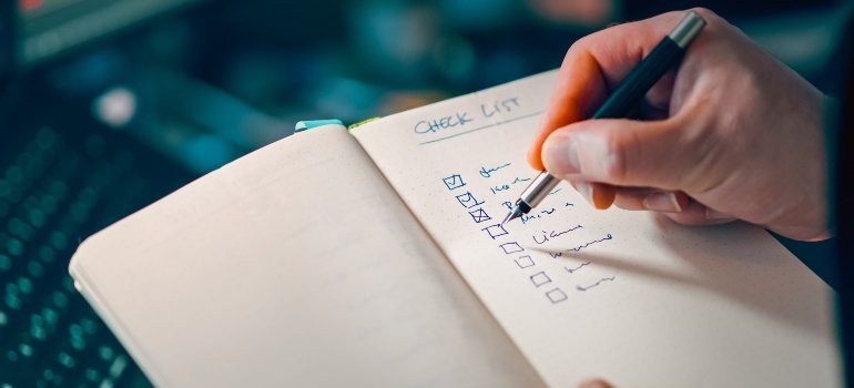 A hand writing an ultimate moving checklist.